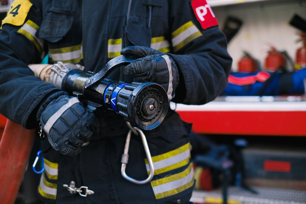 Fire fighter holding a hose: private vs public fire organizations