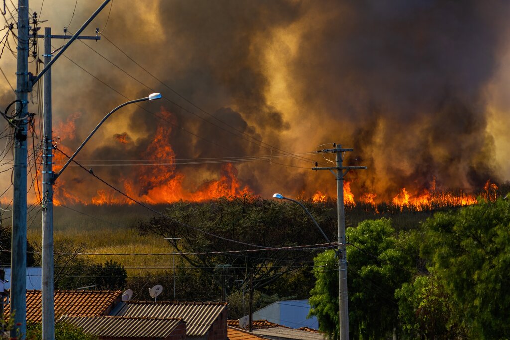 View of a wildfire in the distance with homes at the forefront.