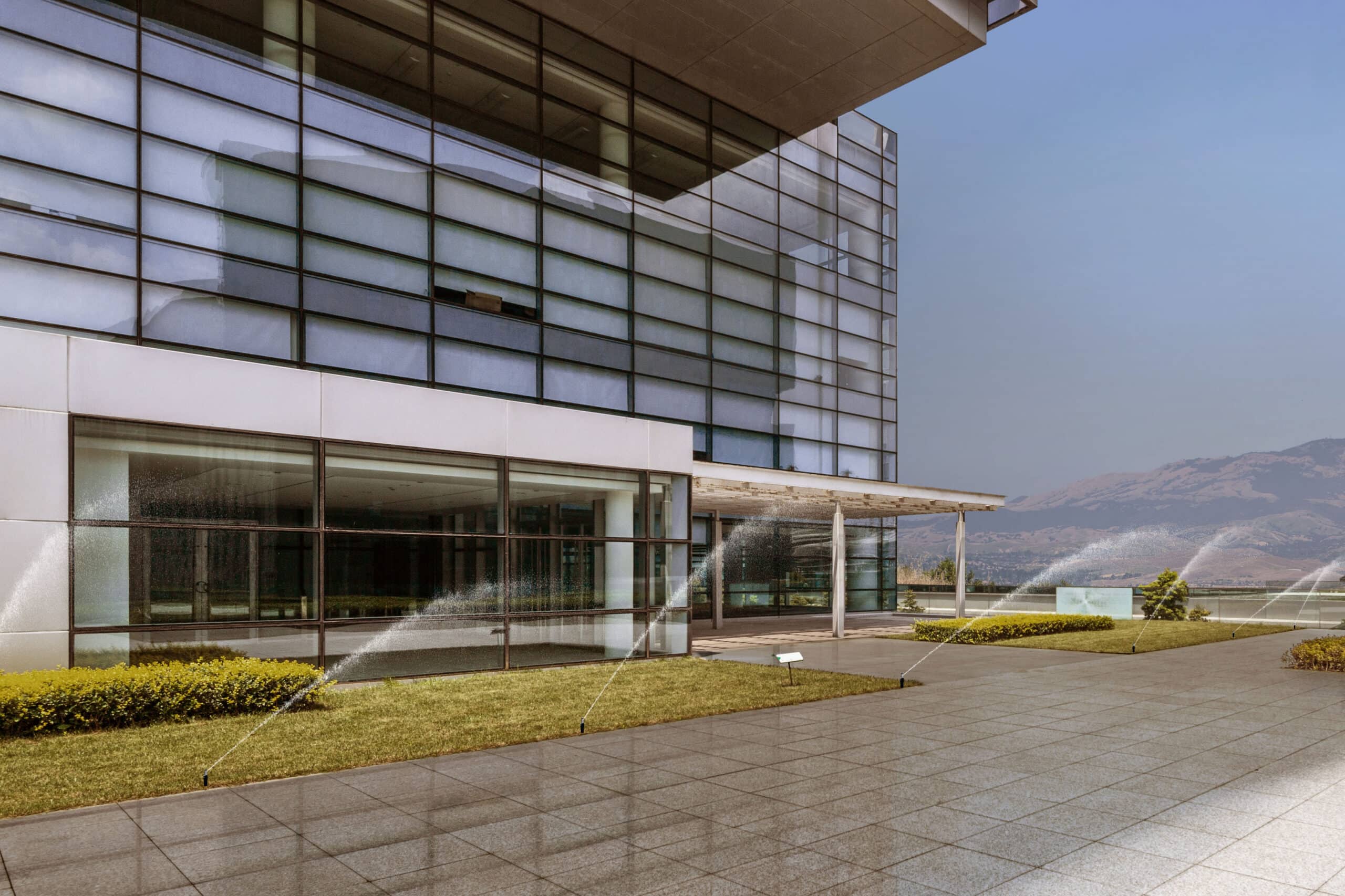 A photo showing Frontline’s commercial wildfire defense system protecting a modern, commercial business by spraying water that cools the exterior landscape.