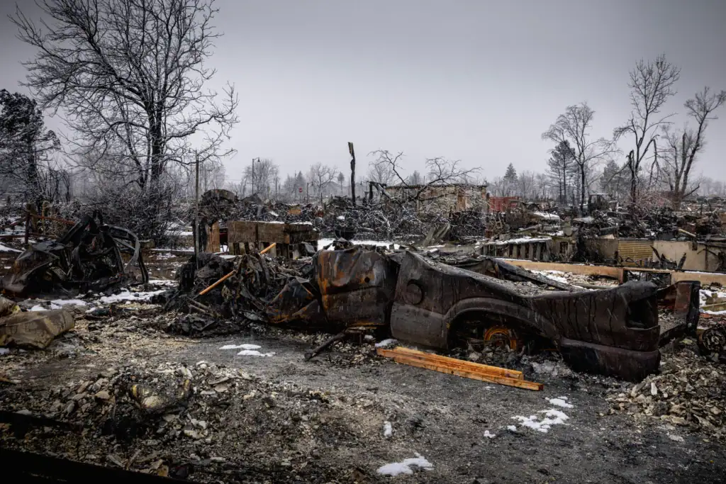 The charred remains of a burned truck and destroyed property, showing the devastating aftermath and need for recovery after Colorado fires.