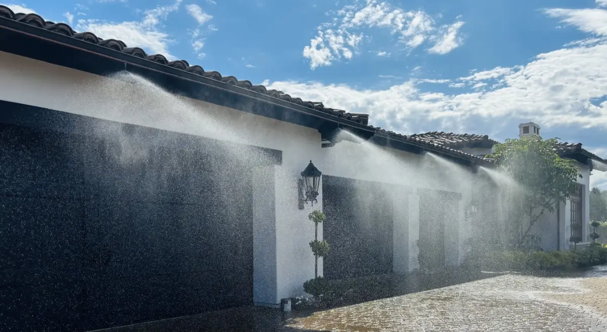 The Frontline wildfire defense system spraying water and Class-A firefighting foam along the exterior roofline and garage of a house.