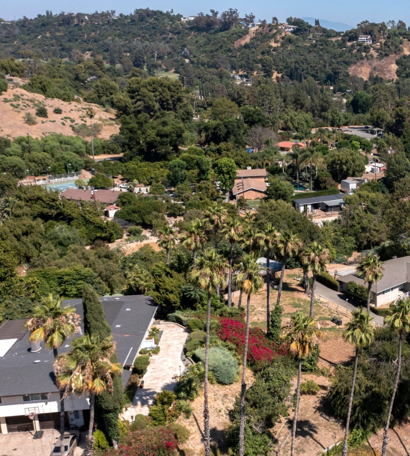 Aerial view of a hillside residential neighborhood nestled in a high-risk wildland-urban interface zone.