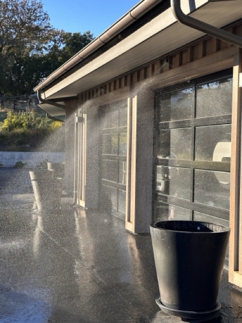 Frontline automated exterior roof and eave sprinklers actively spraying a water and foam mixture to protect a home's garage and exterior walls.
