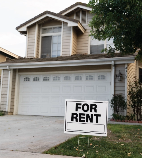 Exterior view of a suburban two-story home with a "For Rent" sign on the front lawn.